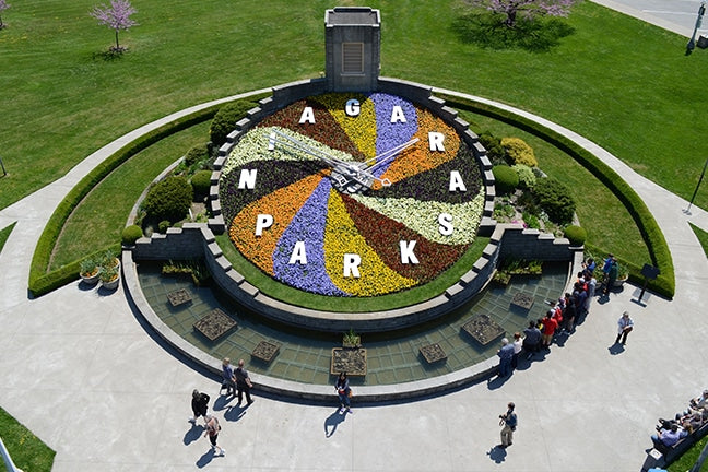 Large colourful flower clock in Niagara Parks with people around it.