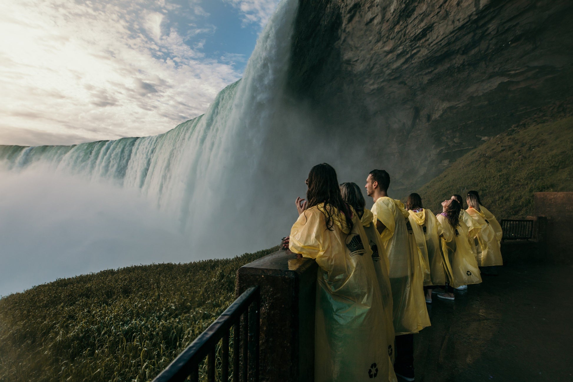 Group of people in yellow raincoats observing a waterfall